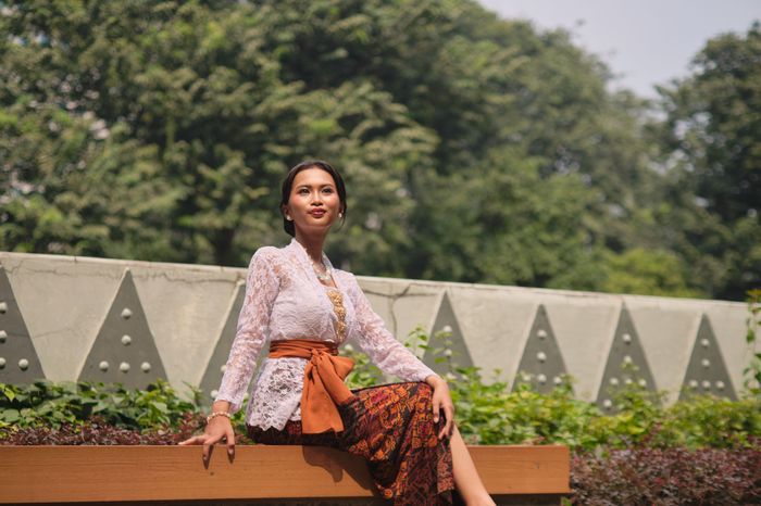 Perempuan duduk mengenakan batik sogan